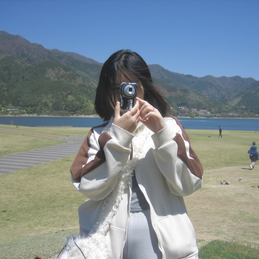 Leyi Yang holding a camera by a lakeside mountain view